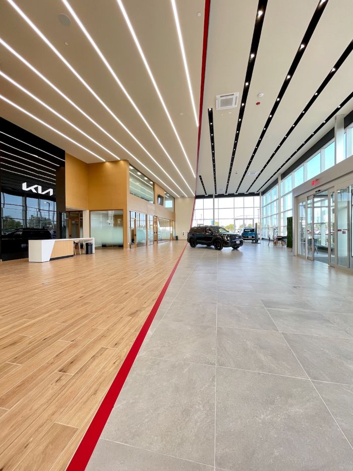 Modern commercial hallway with light wood flooring, clean lines, and a bold red accent stripe